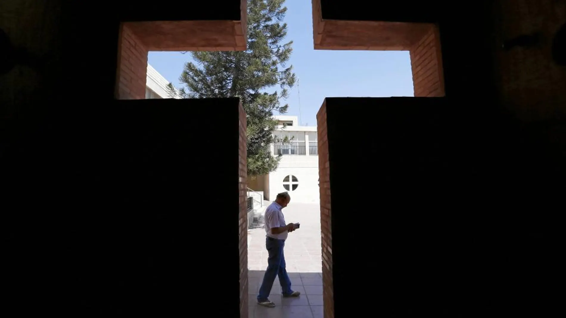 DESPLAZADOS. Un cristiano iraquí de Mosul lee frente a la iglesia del Patriarcado Latino en Jordania