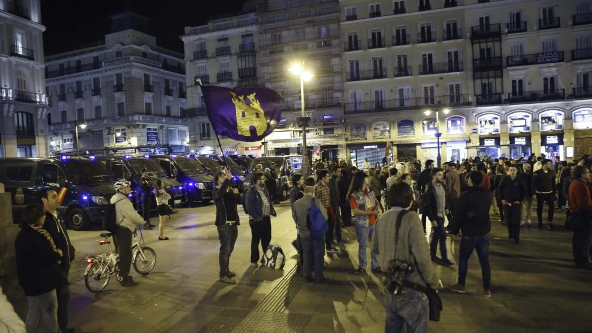 Miembros del movimiento 15M, vigilados por policías nacionales, durante su grito silencioso de la noche del viernes en la madrileña Puerta del Sol