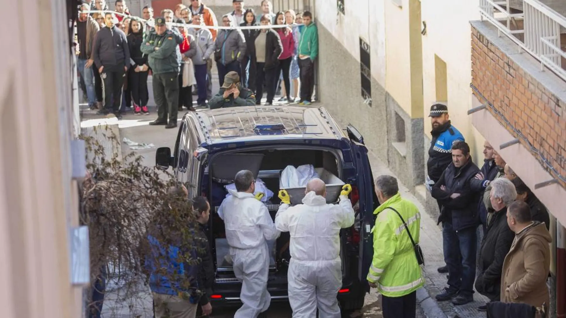Efectivos de los servicios funerarios trasladan el cuerpo de uno de los tres fallecidos en el incendio.