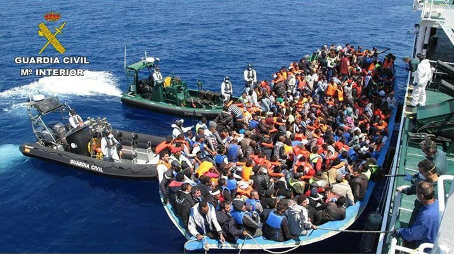 Los inmigrantes junto a la embarcación de la Guardia Civil