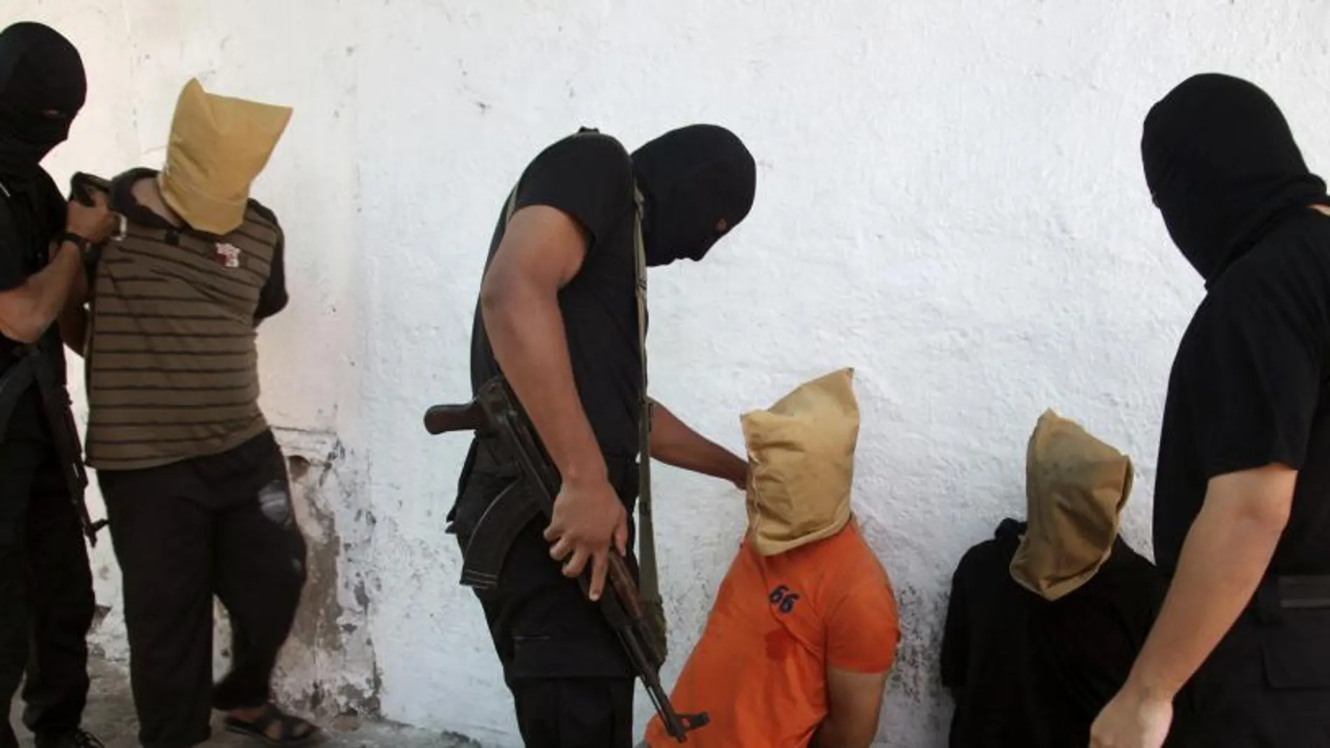 Los militantes de hamas junto a uno de los palestinos a los que ha ejecutado
