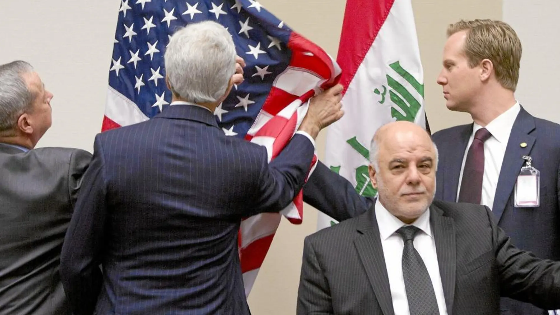 John Kerry, secretario de Estado de EE UU, coloca las banderas en su reunión ayer en Bruselas con el primer ministro iraquí, Al Abadi (centro). Abajo, varios «peshmerga» vigilan en Makhmur, al sur de Erbil.