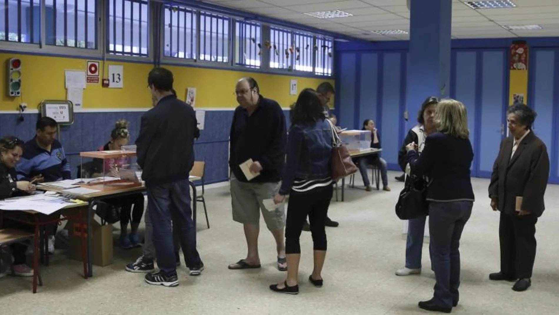 Varias personas hacen cola para depositar su voto en la apertura del colegio electoral en el CEIP Virgen del Portillo en Madrid, al inicio de la jornada electoral que se celebra hoy.