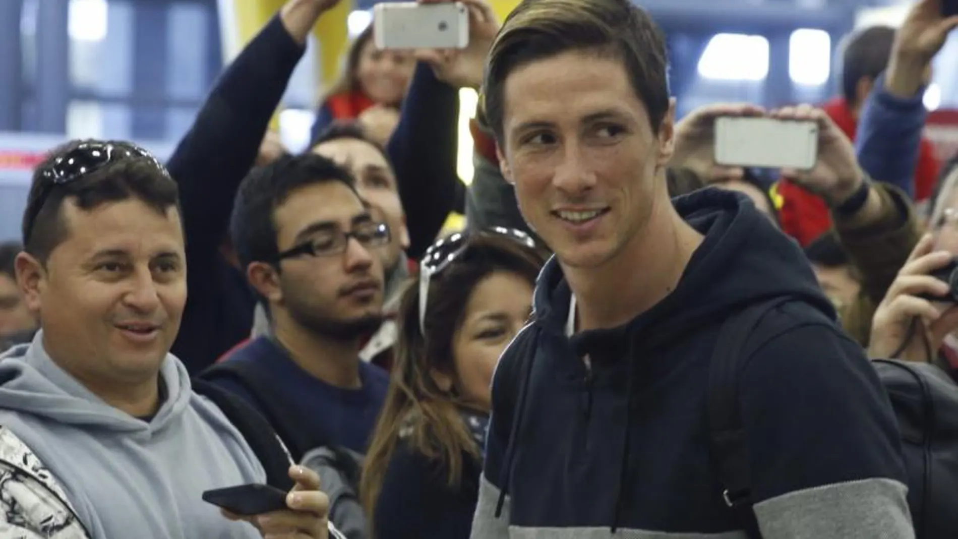 Fernando Torres junto a los aficionados que le esperaban en el aeropuerto a su llegada a Madrid.