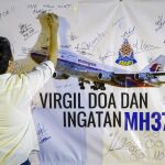 Un hombre escribe un mensaje en un mural durante un acto en recuerdo de las víctimas del vuelo MH370 de Malaysian Airlines.