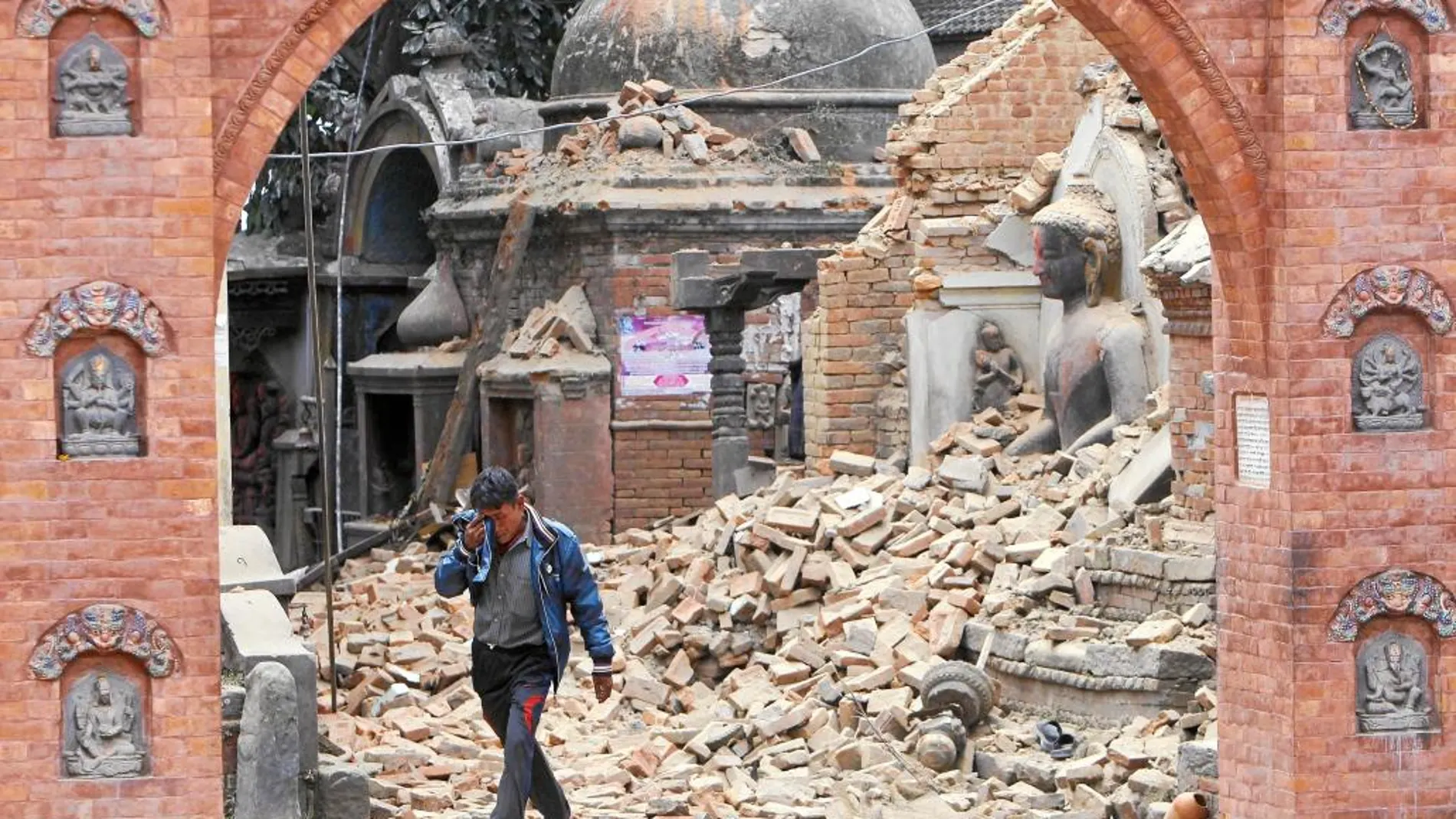 Un hombre llora al pasar junto a una estatua destruida de Buda en Bhaktapur, ciudad Patrimonio de la Humanidad de la Unesco