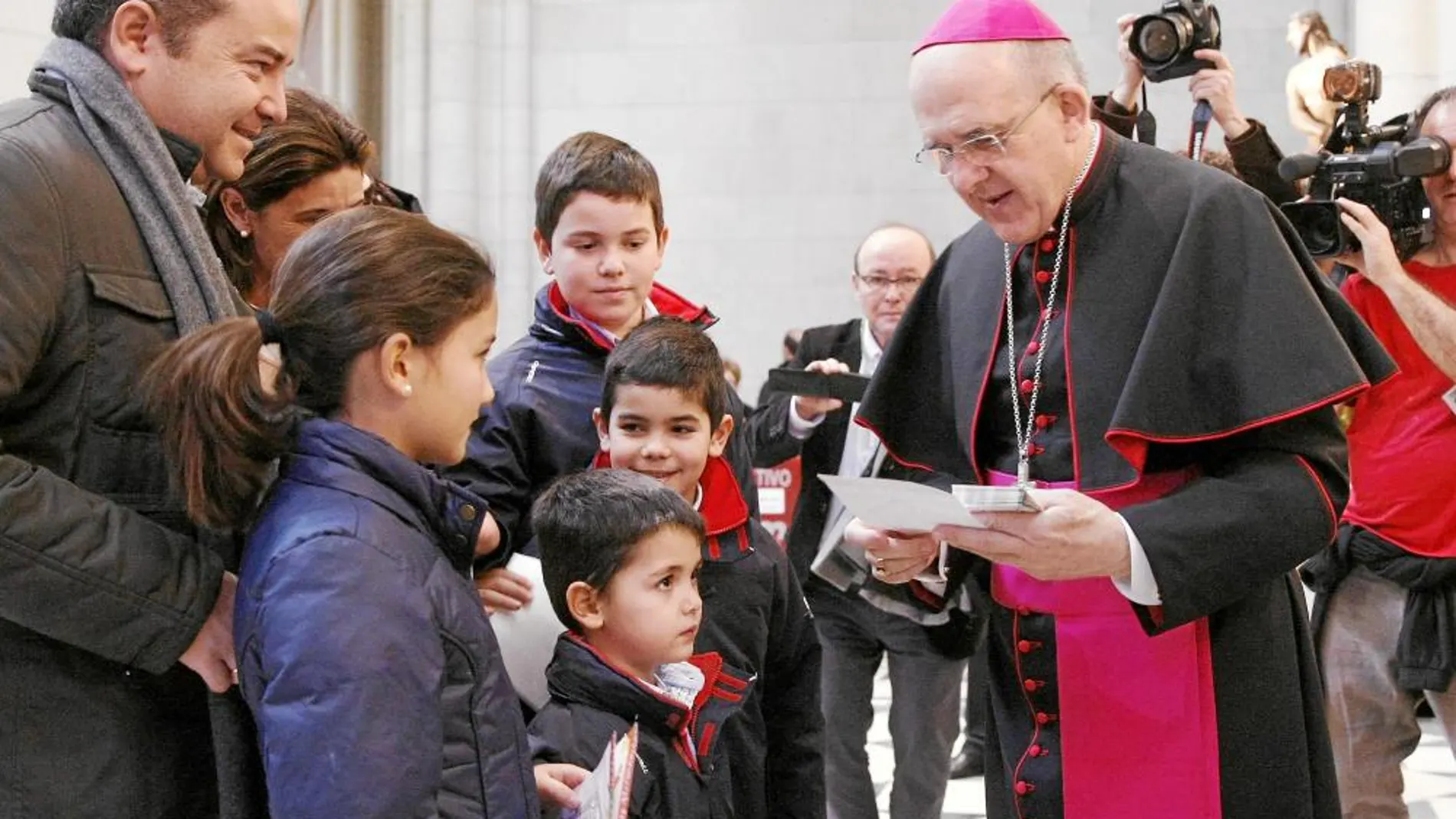 El arzobispo de Madrid, Carlos Osoro, bendice a una de las muchas familias que se acercaron a la Catedral de la Almudena