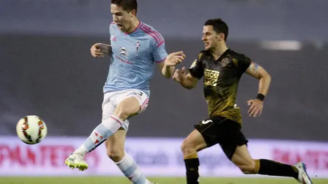 El defensa del Celta de Vigo Andreu Fontás (i) con el balón perseguido por el delantero del Elche Ferrán Corominas durante el partido