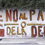 AL BORDE DEL CORRALITO. Una mujer camina en Buenos Aires frente a un mural que clama contra el pago de la deuda