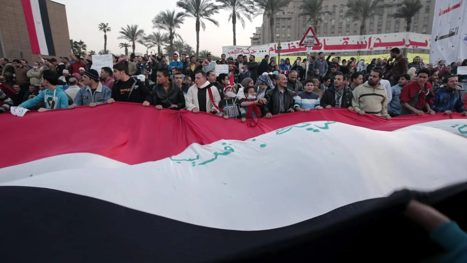 Unos manifestantes sostienen una gran bandera egipcia en la plaza Tahrir de El Cairo, Egipto, durante una multitudinaria protesta coincidiendo con el segundo aniversario de la revolución que derrocó a Hosni Mubarak