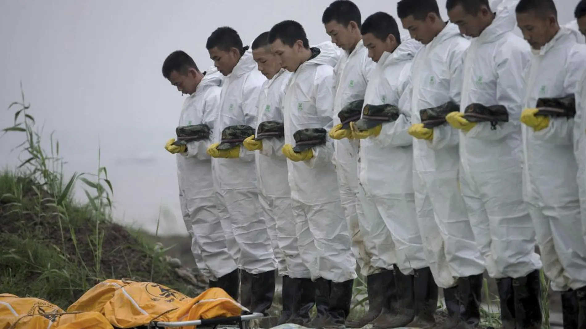 Miembros de los servicios de rescate guardan un minuto de silencio en respeto a las víctimas del barco de pasajeros naufragado en el río Yantsé en China