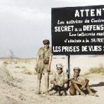 Pierre Leroy, junto otros compañeros, ante el cartel que prohibe el paso y realizar fotografías en zona de pruebas atómicas en el Sáhara argelino