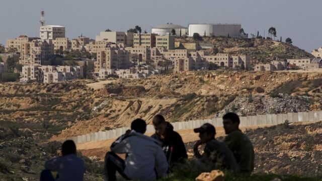Palestinos junto a un asentamiento judío en Cisjordania