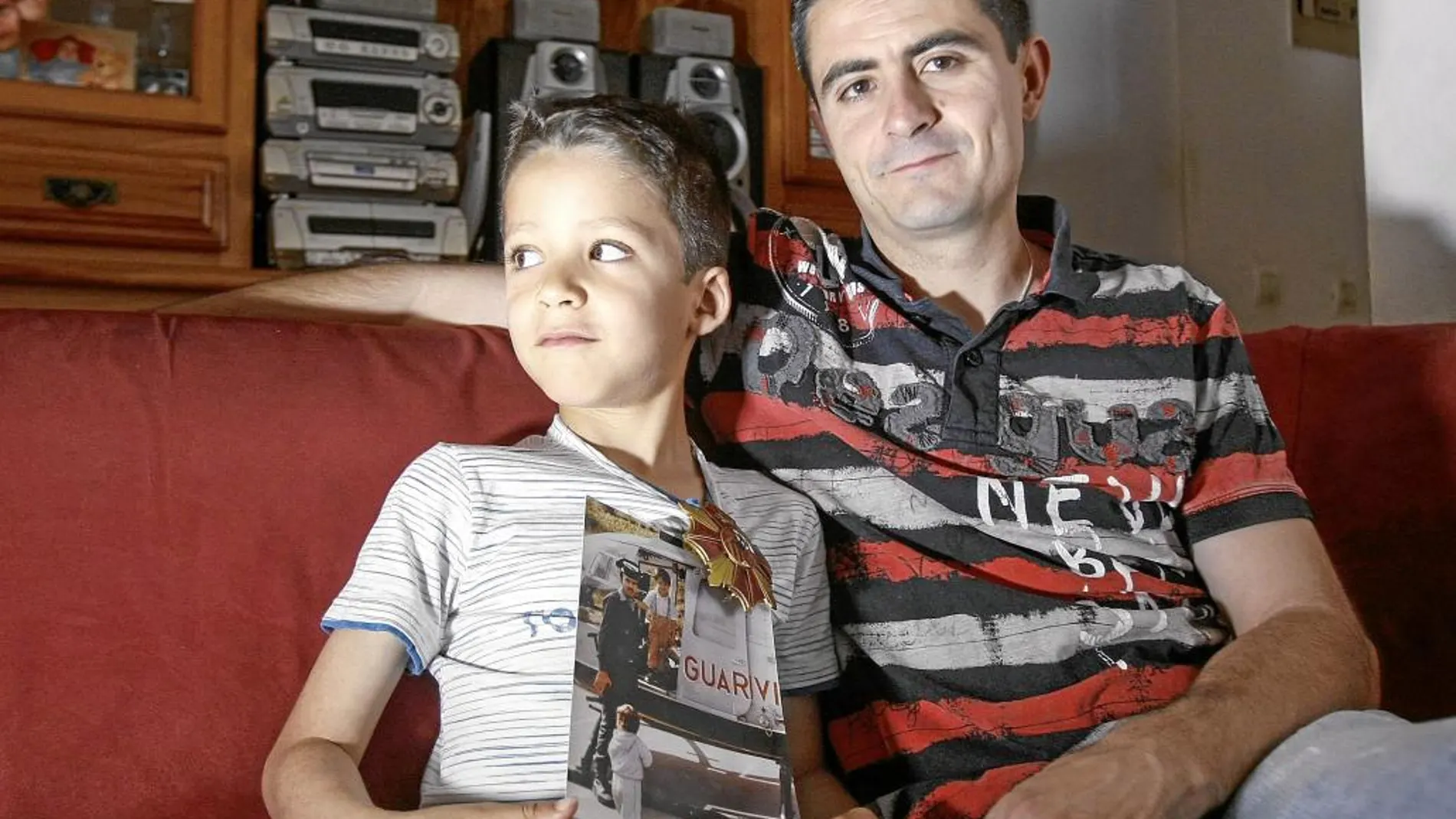 Alejandro Ramos y su hijo Airam, con la medalla que le concedió el Congreso a su padre y una foto en la que aparece con él, cuando era pequeño, en un helicóptero de la Guardia Civil
