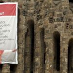 Detalle del cartel colgado en una de las torres de la fachada del Nacimiento de la Sagrada Familia en el que se da la bienvenida al Papa en varios idiomas
