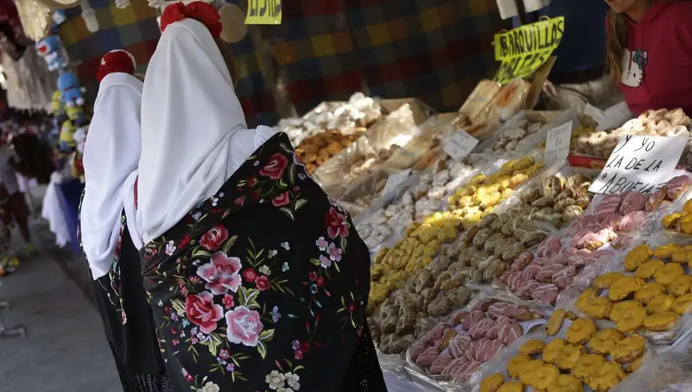 Madrileñas vestidas de chulapas compran rosquillas «tontas» y «listas» en la Pradera de San Isidro.