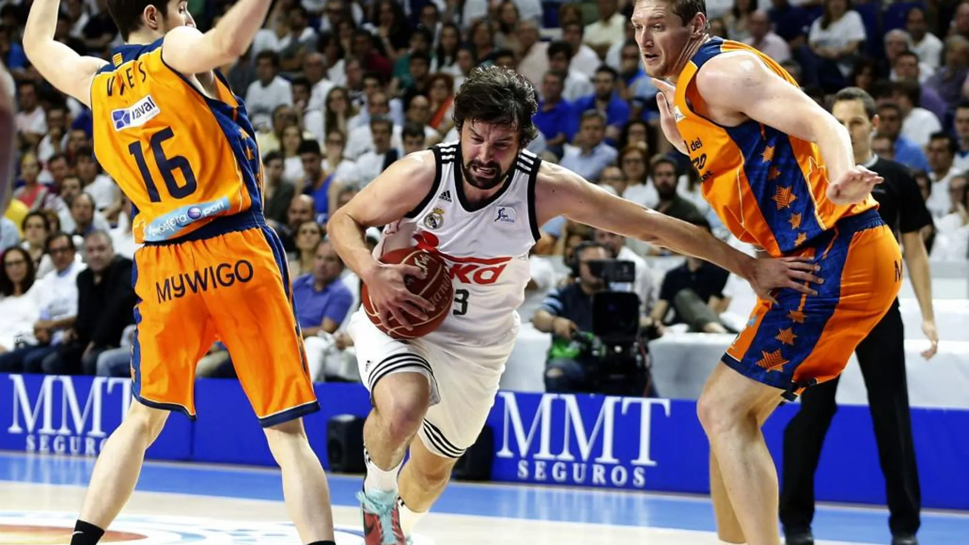 El base del Real Madrid Sergio Llull (c) pugna un balon con el ucraniano Serguéi Lischuk (d) y Guillem Vives, del Valencia Basket