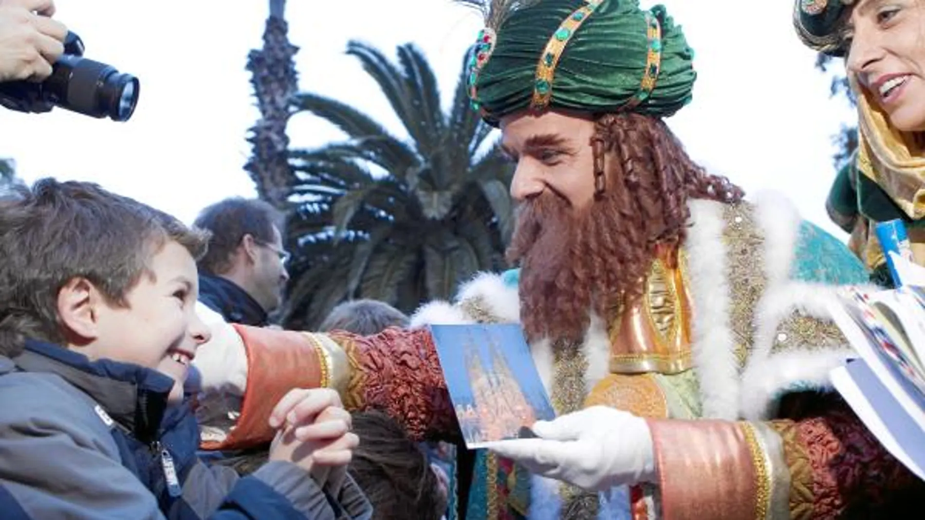 El Rey Gaspar recibe una carta de un niño con la imagen de la Sagrada Familia al comienzo de la cabalgata de Barcelona