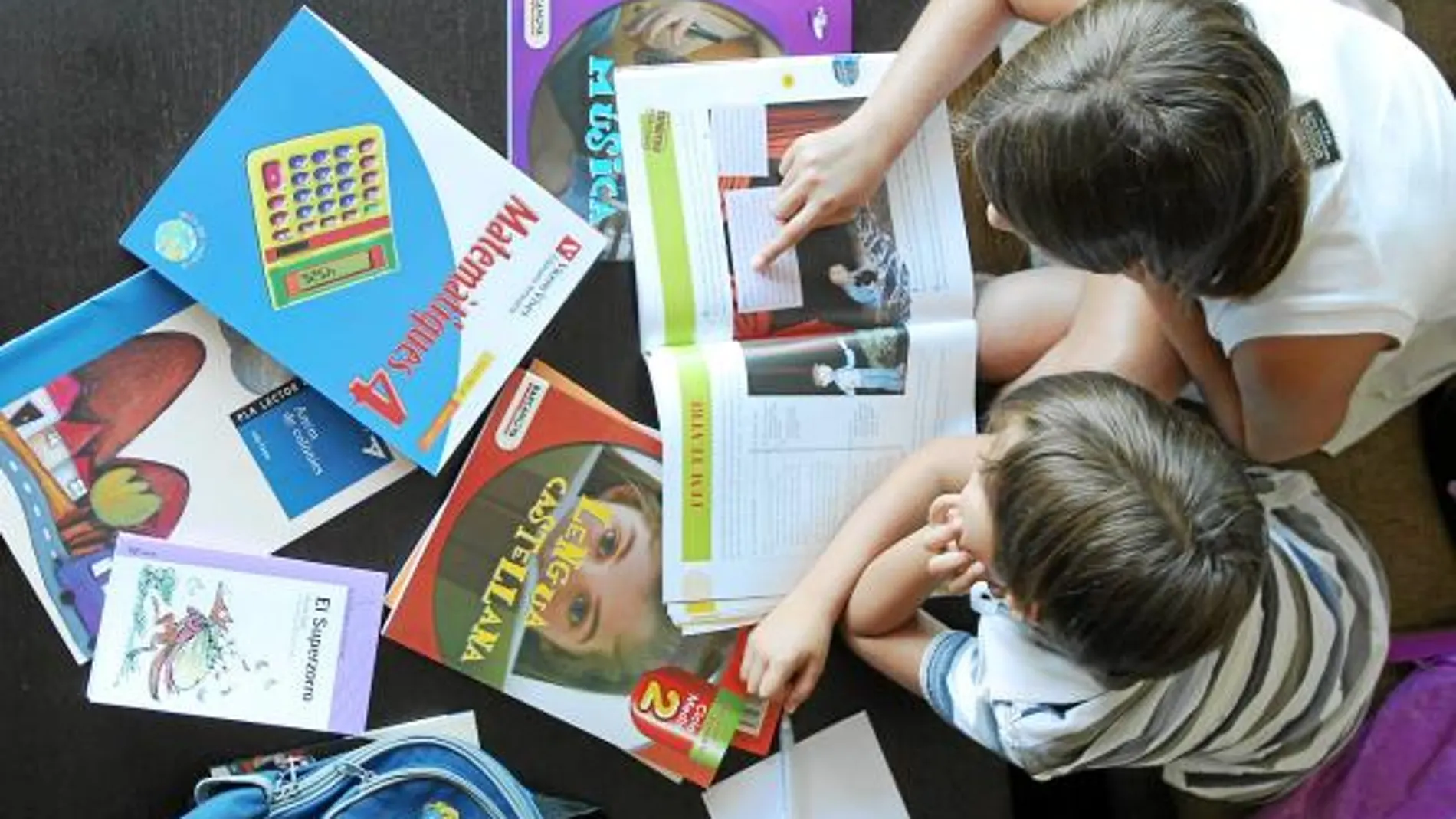 Laura, de 8 años, y su hermano Matías, de 5, miran ilusionados los libros del nuevo curso escolar que empiezan el martes