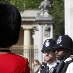 Dos policías londinenses conversan con un gudia de Buckingham Palace