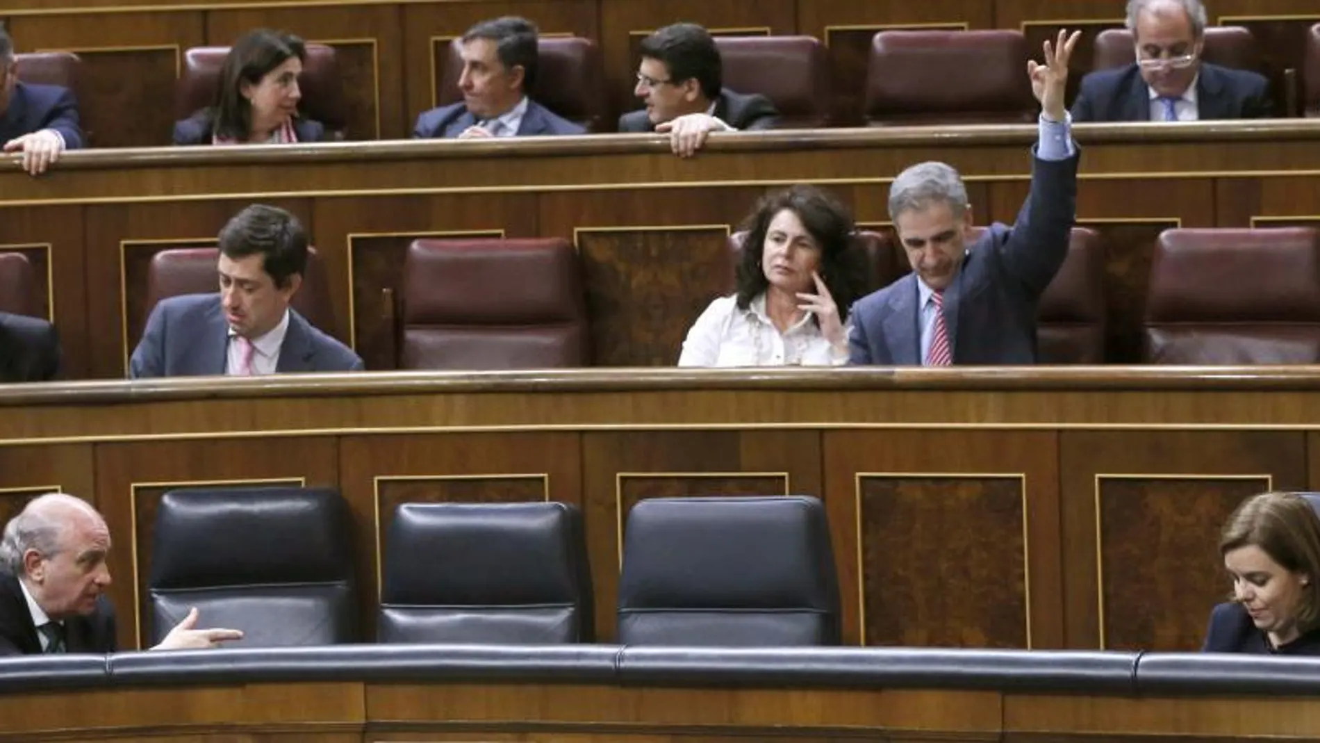 Soraya Sáenz de Santamaría (d), conversa con Jorge Fernández Díaz), mientras el diputado del PP Leopoldo Barreda (atrás) marca el sentido del voto para su grupo, esta tarde durante el pleno del Congreso.