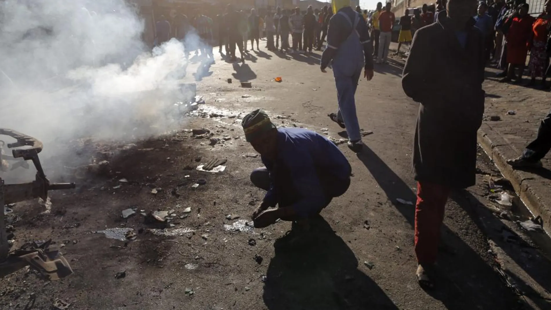 Vecinos partidarios de la expulsión de extranjeros observan un coche incendiado en un ataque xenófobo registrado en el centro de Johannesburgo