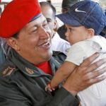 Hugo Chávez sostiene en brazos a un niño mientras espera la llegada del presidente ecuatoriano, Rafael Correa, en una base militar de Caracas