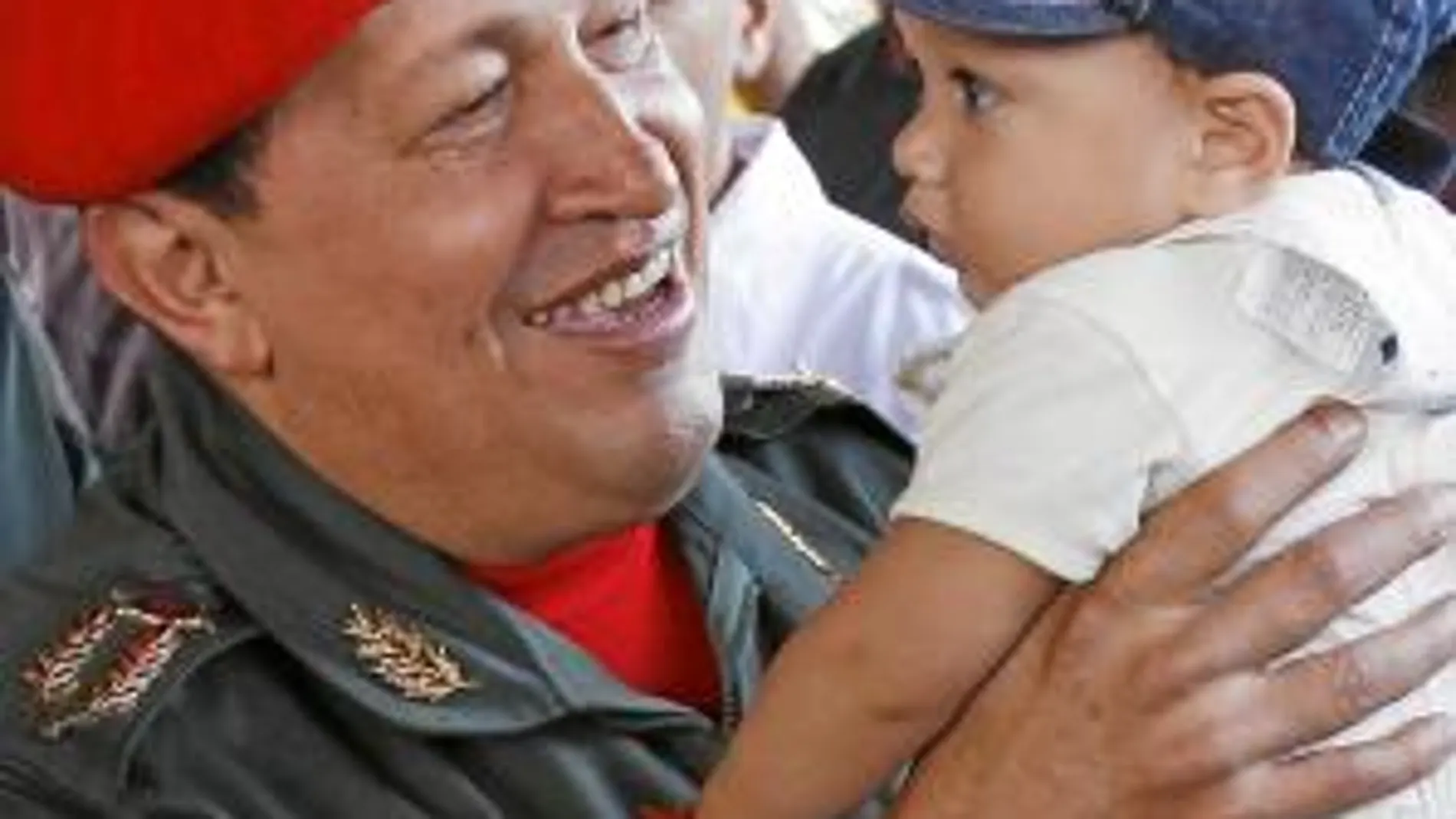 Hugo Chávez sostiene en brazos a un niño mientras espera la llegada del presidente ecuatoriano, Rafael Correa, en una base militar de Caracas