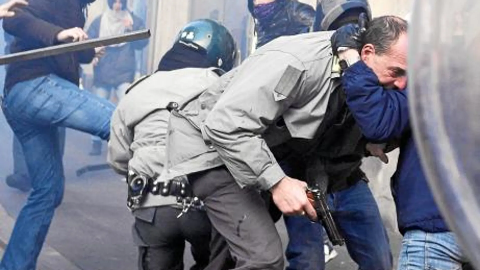 Un oficial empuña su pistola mientras forcejea con un individuo en los disturbios del martes en Roma