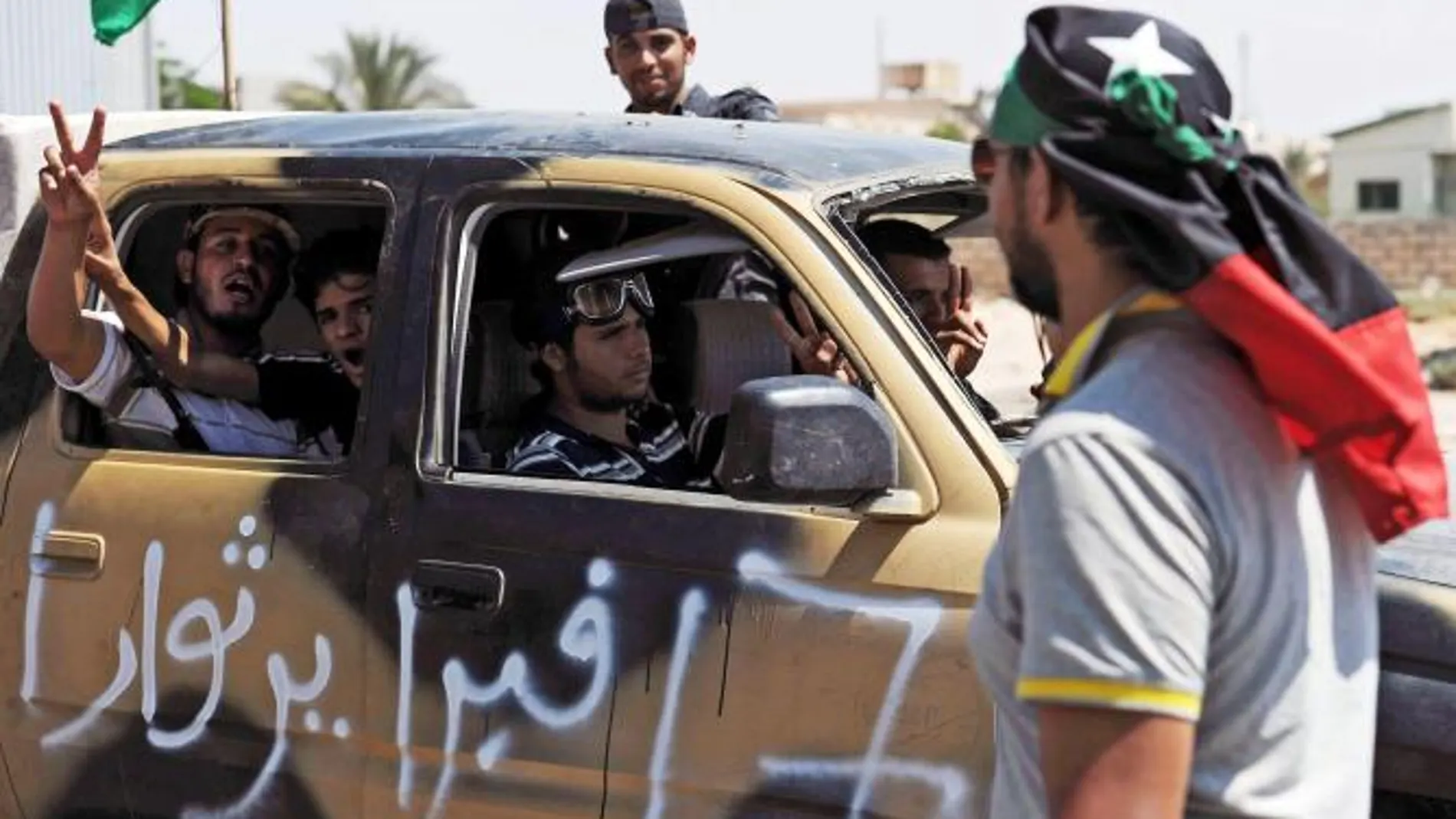 Un coche con rebeldes libios pasa un puesto de control en Trípoli