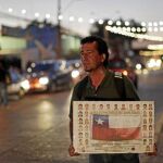 Un hombre sujeta un cartel con la bandera chilena y los rostros de los 33 mineros cerca del Hospital de Copiapó