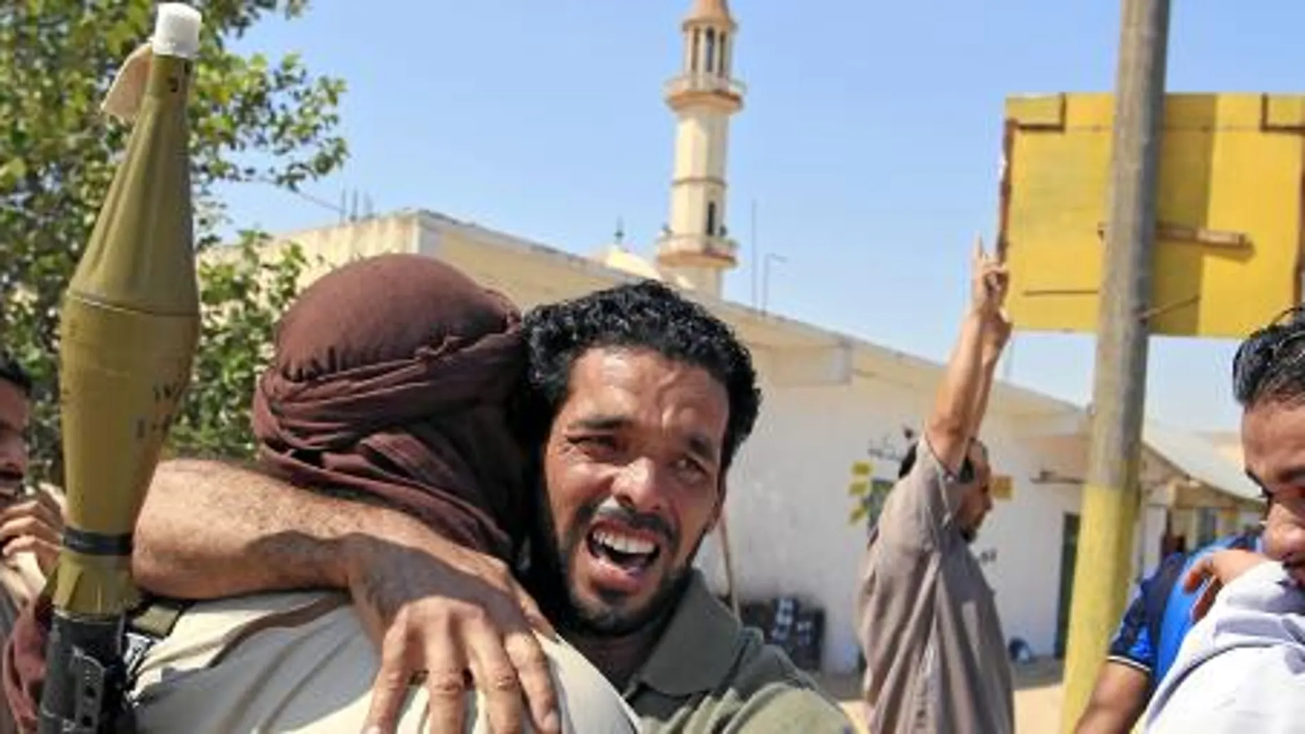 Rebeldes libios se abrazan, ayer, en Trípoli
