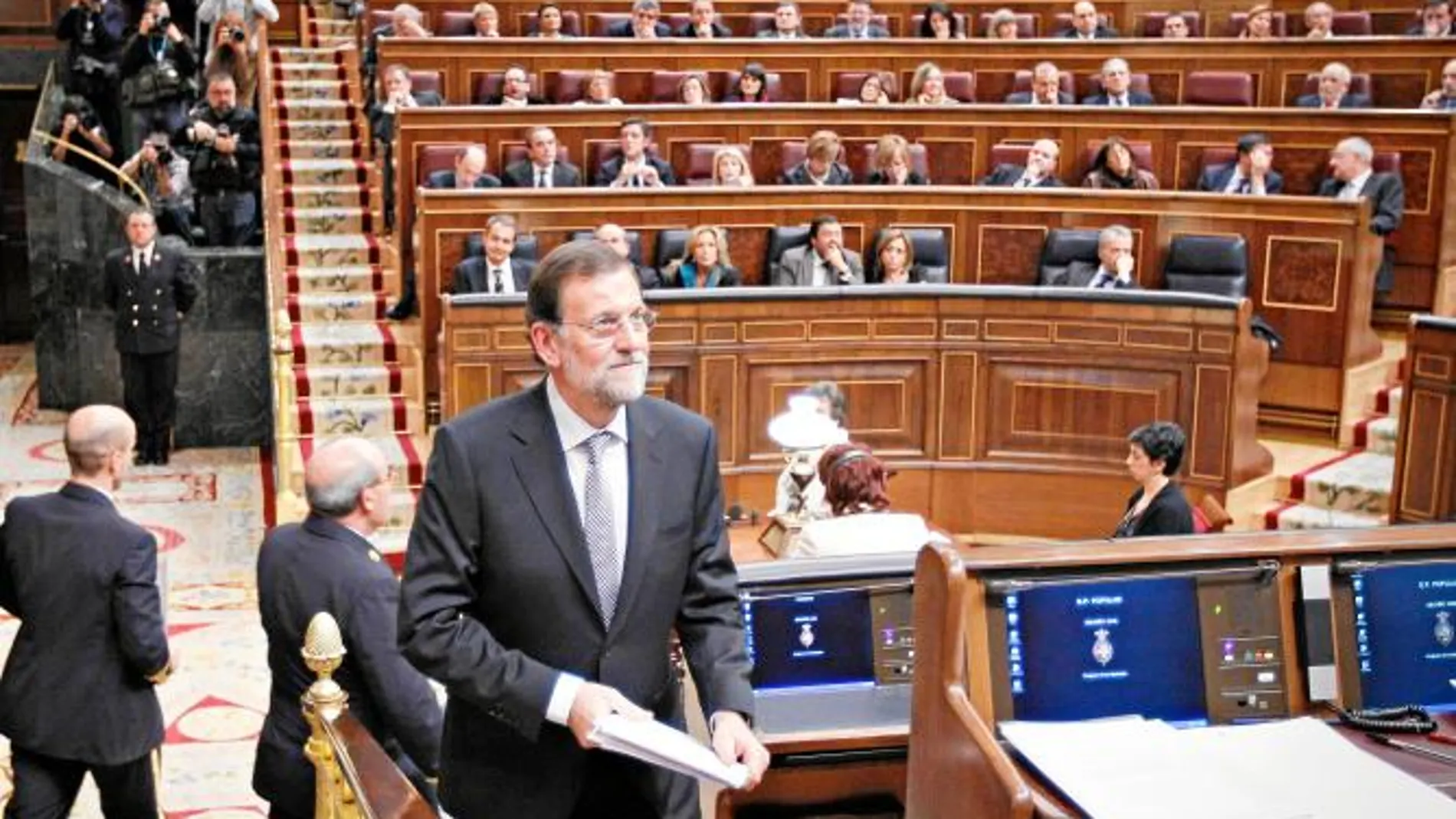 Mariano Rajoy regresa a su escaño tras pronunciar ayer el discurso de investidura en el Congreso de los Diputados con Zapatero al fondo