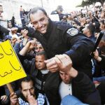 Varios manifestantes llevan a hombros a un policía durante las protestas de ayer en Túnez