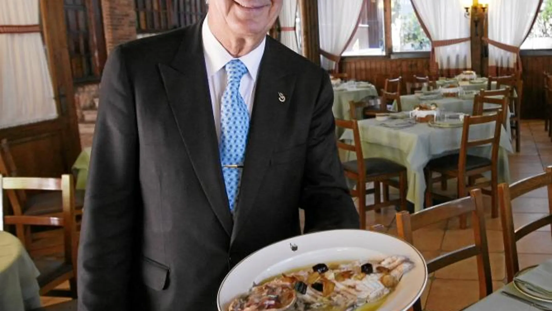 Leoncio González Molina muestra un plato de besugo a la espalda