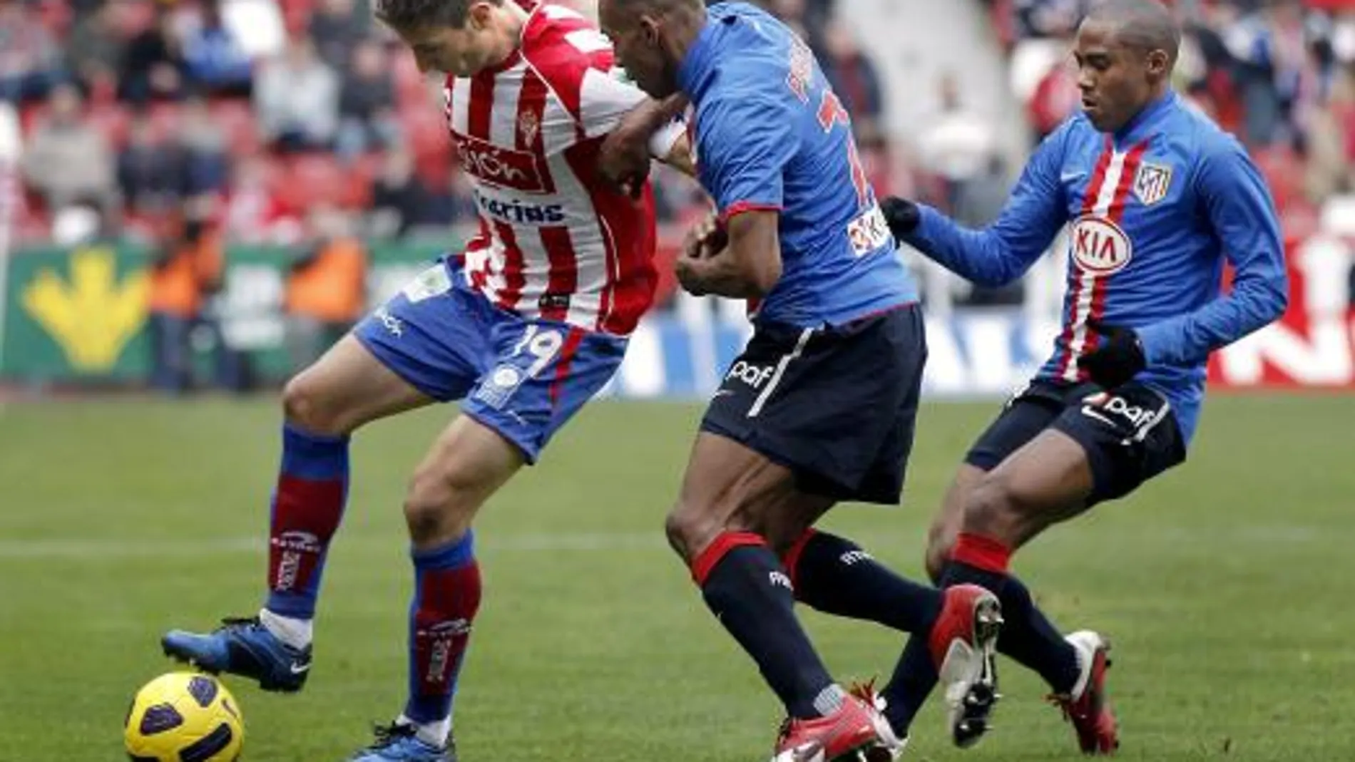 El mediocentro uruguayo del Sporting de Gijón Sebastián Eguren (i) protege el balón ante los jugadores del Atlético de Madrid el colombiano Luis Amaranto Perea (c) y el brasileño Elías Mendes durante el partido.