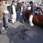Varios hombres observan los restos de sangre en el lugar donde se produjo el tiroteo, en una calle de Lahore