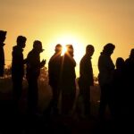 Refugiados provenientes de Libia hacen cola para recibir la comida, en el campamento montado cerca del paso fronterizo de Ras el Jedir, Túnez,
