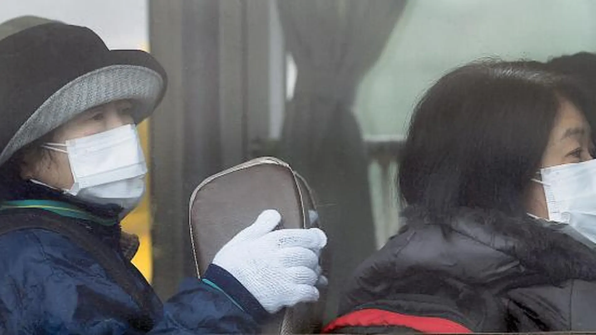 Unas japonesas, en un autobús, con mascarillas para protegerse.