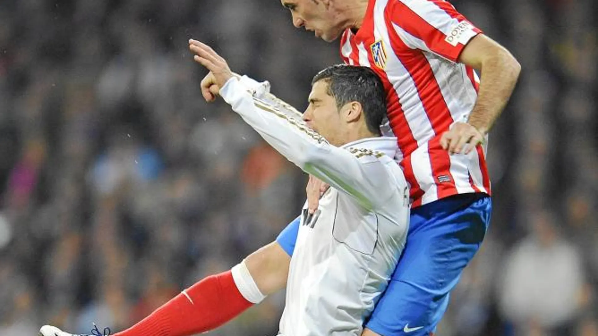 Godín salta por encima de Cristiano Ronaldo y despeja la pelota de cabeza en el derbi jugado ayer en el Bernabéu