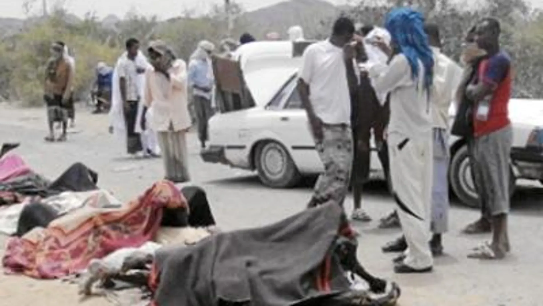Un grupo de personas observa los cadáveres de los hombres que murieron ayer en la fábrica de armas de Yaar, al sur de Yemen