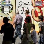 Varias personas pasean ante una pintada a favor de ETA dentro del recinto festivo en el Arenal bilbaíno