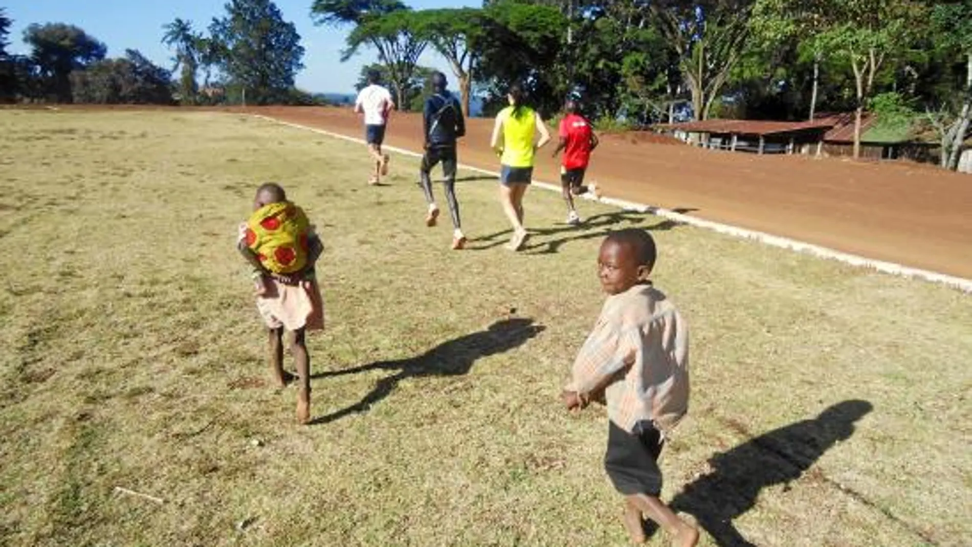 ARTURO CASADO, en cabeza del grupo de atletas perseguido por dos niños en la pista de Iten