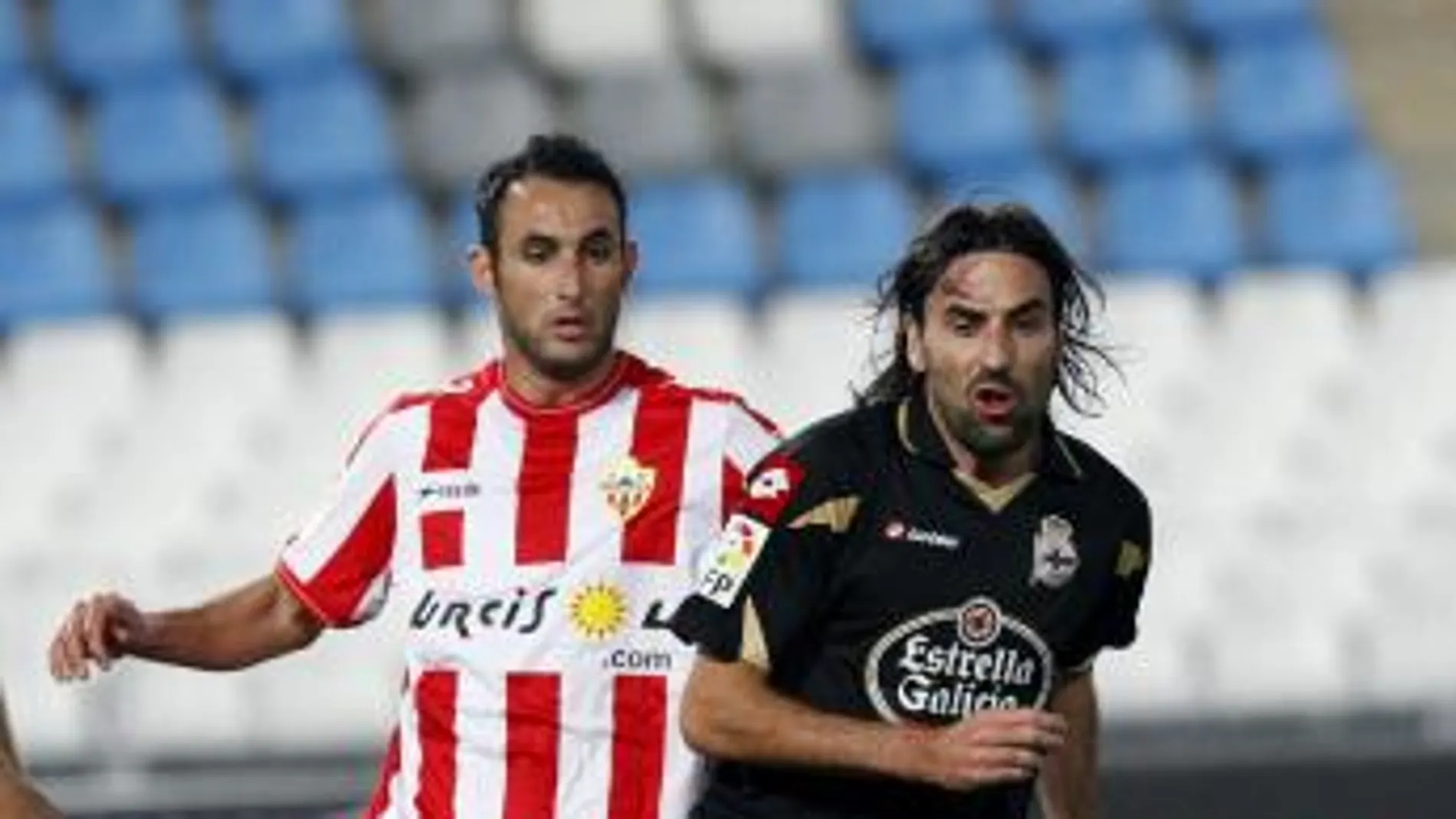 El defensa del Almería Juanma Ortiz (i) disputa un balón con el centrocampista Juan Rodríguez, del eportivo de La Coruña