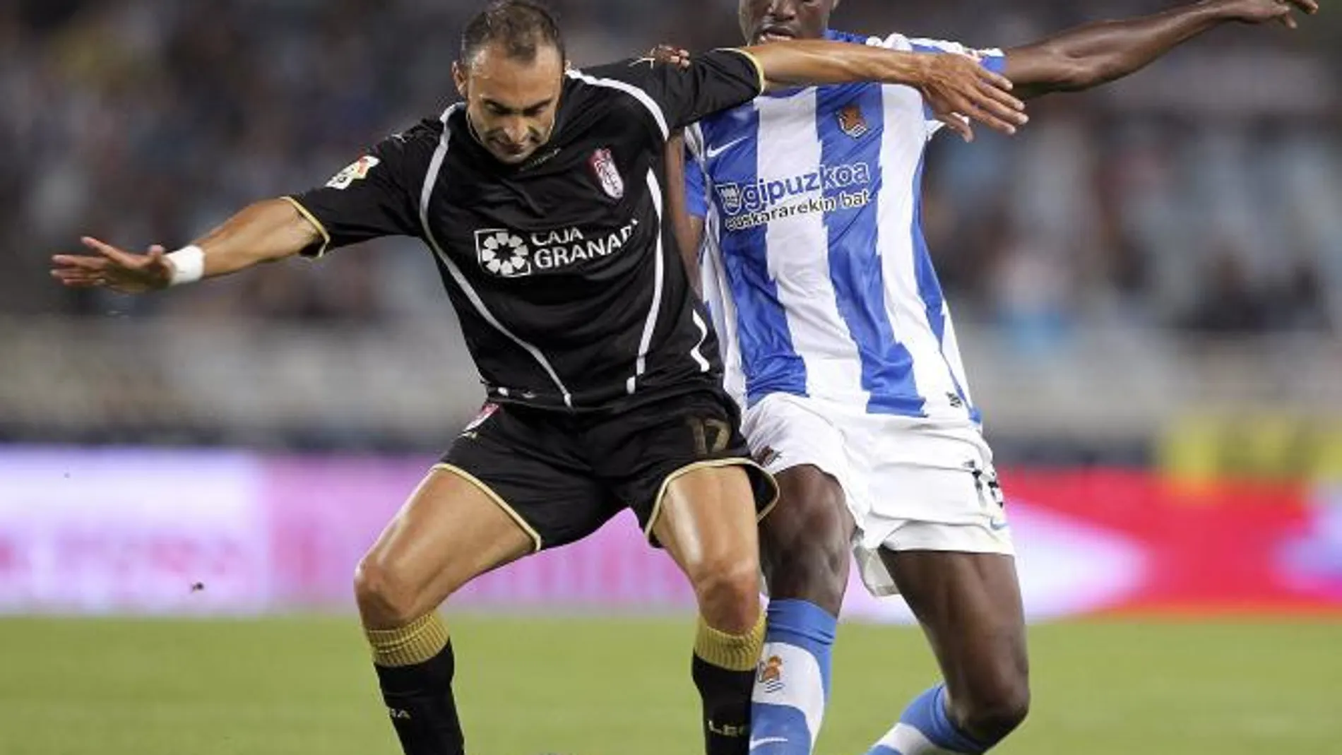 El centrocampista keniata de la Real Sociedad, Macdonald Mariga (d), pelea un balón con el centrocampista portugués del Granada Carlos Martins