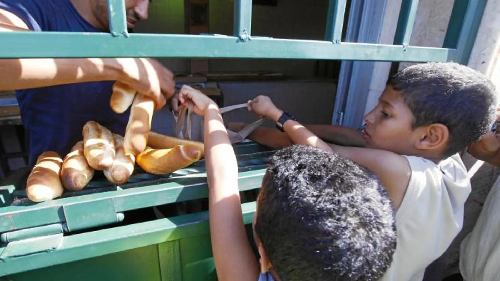 Varios niños hacen cola para recoger pan en una tienda cerca de Trípoli