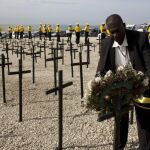 Un haitiano coloca una corona de flores junto a las cruces que recuerdan a las víctimas del terremoto