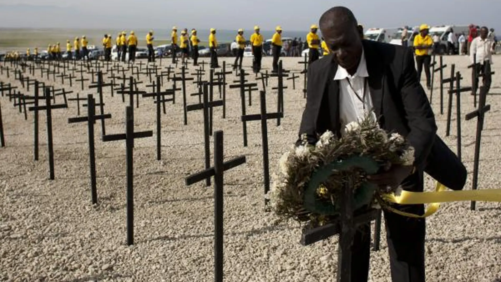 Un haitiano coloca una corona de flores junto a las cruces que recuerdan a las víctimas del terremoto
