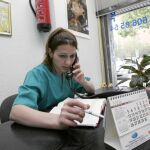 Una mujer atiende al teléfono en la recepción de una clínica dental en la que trabaja