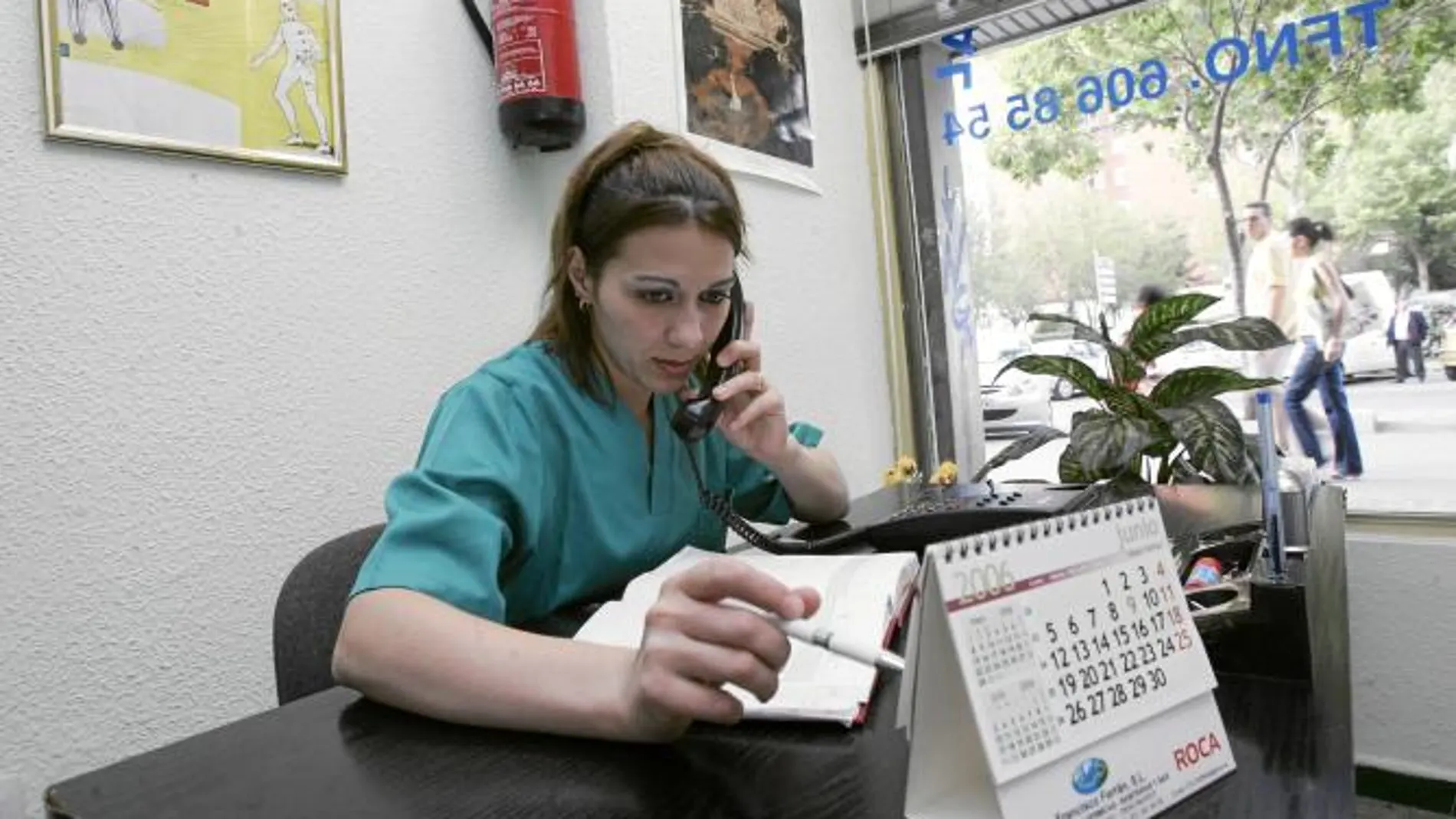 Una mujer atiende al teléfono en la recepción de una clínica dental en la que trabaja